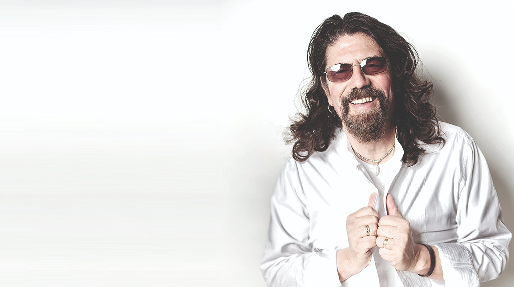 Phil Bates wearing white shirt and glasses, standing in front of a white background, smiling, looking at camera