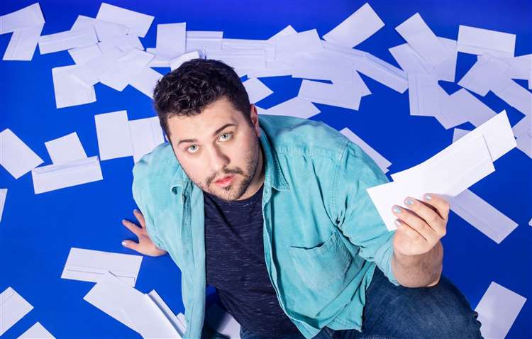 Will Jackson sat amongst envelopes scattered across the floor. Will is holding in his left hand two envelopes.