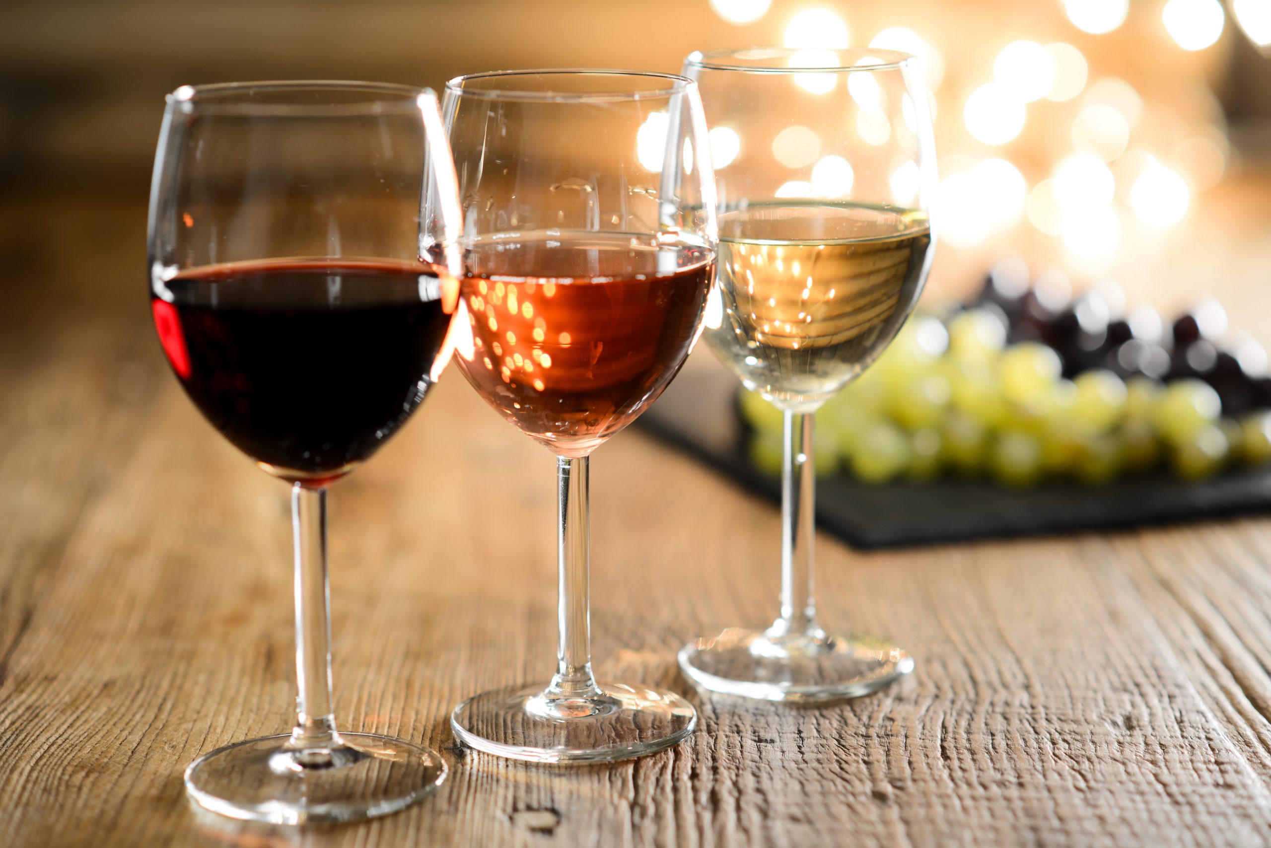 On a wooden table three glasses of wine in a row, red, rose and white