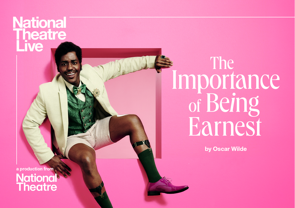 Promotional poster for National Theatre's The Importance of Being Earnest, showing a smiling Ncuti Gatwa wearing cream Edwardian suit jacket, green waist coat and cream shorts, sat, leant back