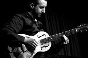 Black and white photo of Glen Bartley playing his guitar