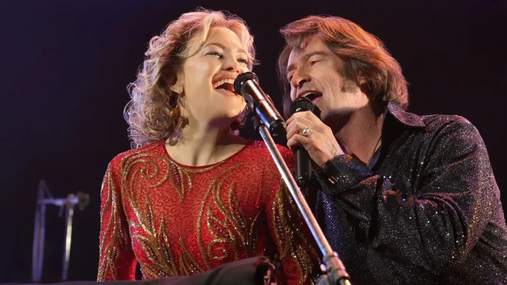 Hugh Jackman and Kate Hudson lean into a microphone, singing