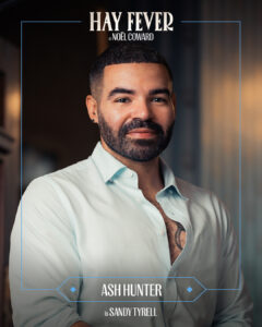 A close-up portrait of Ash Hunter smiling, on a magazine cover titled Hay Fever by Noël Coward, with a blue bordered frame and subtitle at the bottom.