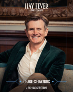Promotional poster portrait of Charles Edwards as Richard Greatham for Hay Fever; smiling man in a dark green velvet blazer.